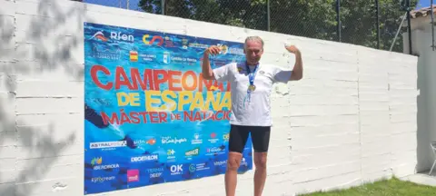 Supplied Nick Parkes pictured in a white T-shirt and black shorts with a medal around his neck cheering after a win at a Spanish swimming championship