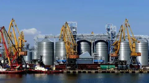 Future Publishing / Getty a ship is loaded with grain in front of silos at Odessa's port