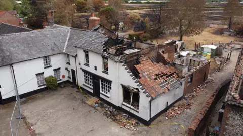 Shaun Whitmore/BBC Buildings in Ashill damaged by fire