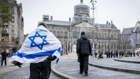 Un hombre de la EPA con bandera israelí camina por el centro de Ámsterdam