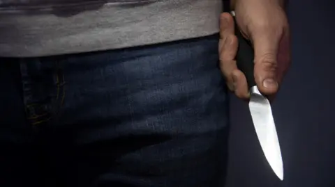A close up of a man's hand holding a sharp knife