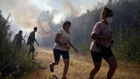 AFP via Getty Images People run away from the fires in Spain