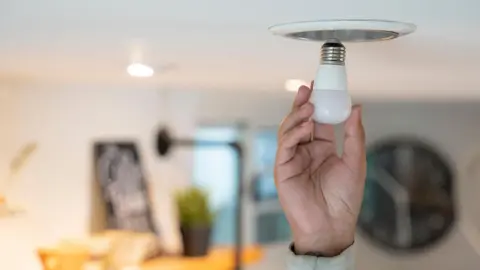 A person is seen changing a light bulb