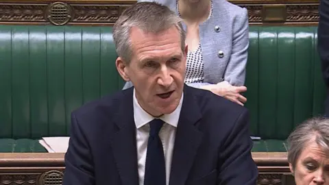 Dan Jarvis, yang memiliki rambut abu -abu pendek dan mengenakan setelan biru tua, berbicara kepada House of Commons 