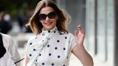 Victoria Starmer wearing a polka dot dress and sunglasses attends a show during London Fashion Week September 2024