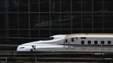Bullet train facing left as it pulls into Tokyo station. 