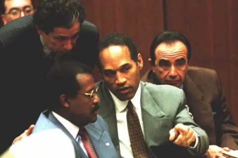 Getty Images Johnnie Cochran, OJ Simpson and Robert Shapiro sitting in court with Robert Kardashian leaning over them