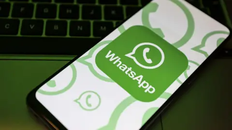 A stylised image shows the Whatsapp logo on a mobile phone screen, placed on a keyboard 