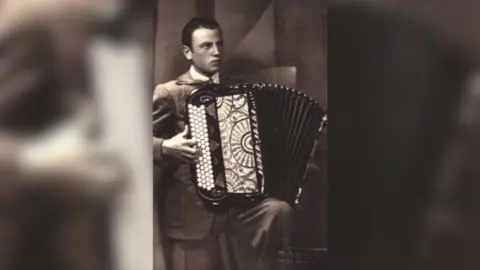 Emilio Allodi Black and white photo of Bruno Allodi wearing a smart suit, playing his accordion