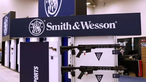 A sign reading 'Smith & Wesson' with large assault rifles below