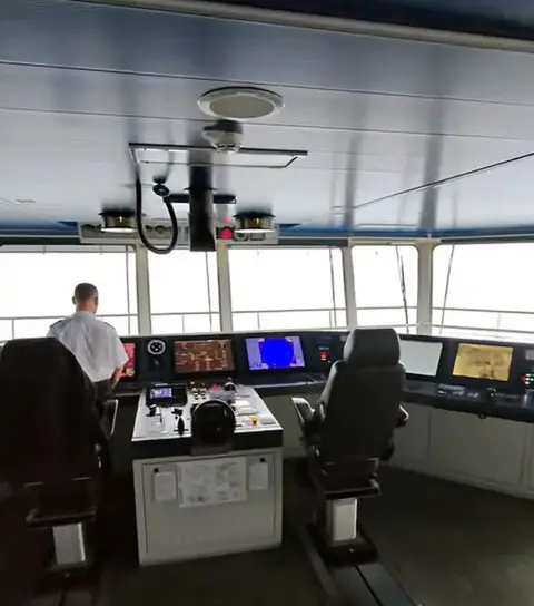 Youtube The bridge of a ferry including a member of staff who is being filmed from behind.