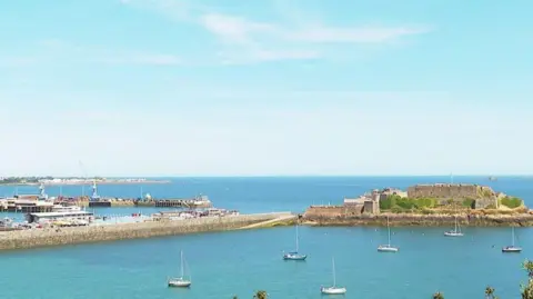 BBC The harbour in Guernsey with a number of boats dotted on the sea.