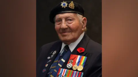 PA Media A headshot of Mr Kersh, who is wearing his unit beret and his medals and smiles at the camera