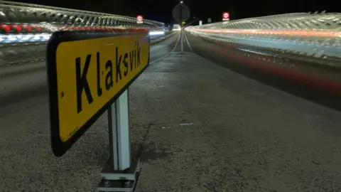 Vehicles streak past the two lanes in a tunnel either side of a yellow sign which reads: "Klaksvik"