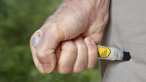 Getty Images person stabbing thigh with epiPen