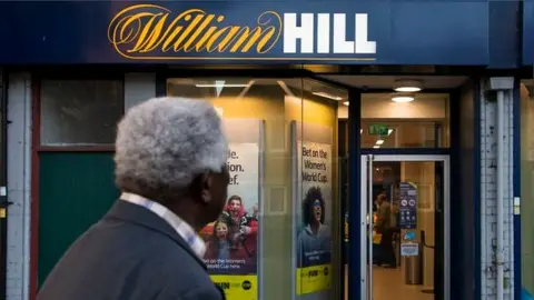 Getty Images Man stands outside William Hill shop