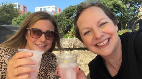 Breast Friends Two woman holding plastic cups filled with drinks, smiling at the camera