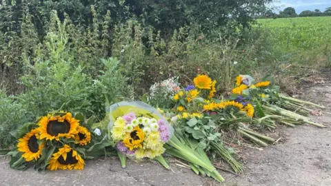 Andrew Turner/BBC Floral tributes left on the roadside at Stalham