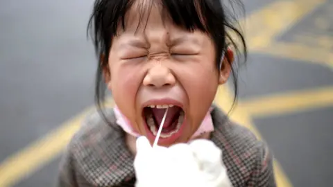 Getty Images A girl reacts to the throat swab in the mandatory all-inclusive Covid-19 test in Wuhan in central China's Hubei province Sunday, March 06, 2022