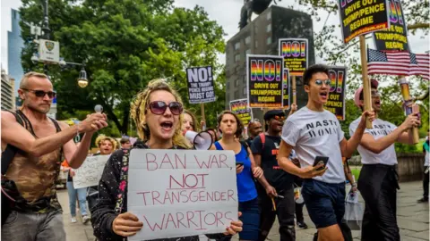 Pacific Press via Getty Images 2017/07/29: A group of New Yorkers gathered at Columbus Circle across the Trump International Hotel and Tower New York in Central Park to raise their voices in protest against discrimination towards the LGBT community, in the aftermath of the Trump/Pence regime decision to ban transgender people from serving in the U.S. military