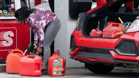 Getty Images Woman filling up petrol cans in Benson, North Carolina, on Wednesday.