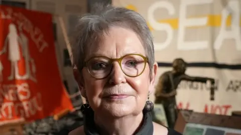 A woman with short grey hair and glasses