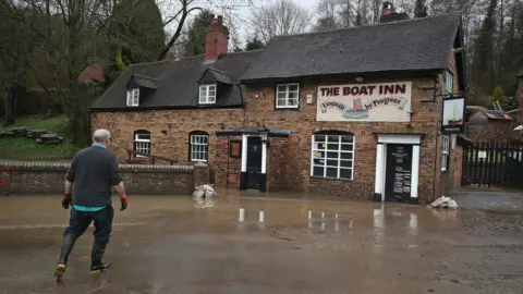 PA Media A resident at the Boat Inn in Jackfield near Ironbridge after flood water has started to recede