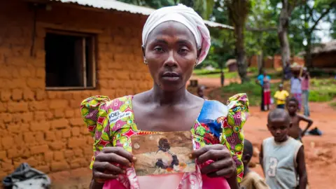 Benoit De Freine Suriya Muyombe holds a picture of her missing child