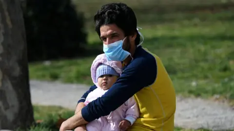 Reuters A man holds a baby outside the AHEPA hospital, where the first confirmed coronavirus case is being treated, in Thessaloniki, Greece,