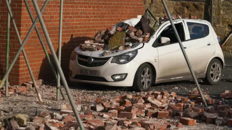 PA Media A car crushed by fallen bricks in Seaton Sluice, Northumberland