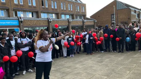 Shariqua Ahmed/BBC Bernadette, a woman wearing a white-T shirt and black trousers addressing a crowd.