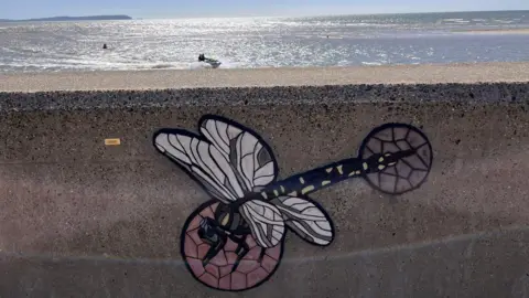 BCP Council Dragonfly in mosaic set into a sea wall with the sea behind.