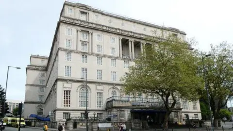 Exterior image of the Adelphi Hotel in Liverpool - it is white bricked with Georgian style windows and has two trees in front of it