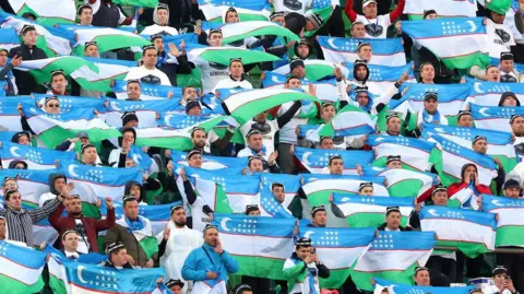 Uzbekistan's fans hold aloft the national flag during a match