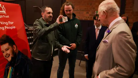 PA Media Magician Steven Frayne holds a pack of cards up for King Charles.