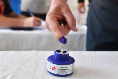 FETHI BELAID / AFP A Tunisian dips his finger in ink after casting his vote in the presidential election at a polling station in Tunis.