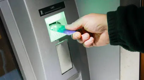 Close up of an anonymous hand pushing a bank card into a cash machine. 