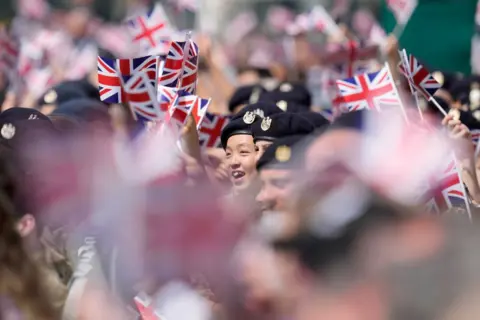 Kin Cheung/Getty Images People in uniform wave flags