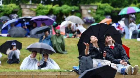 Reuters Spectators holding their umbrellas in the rain