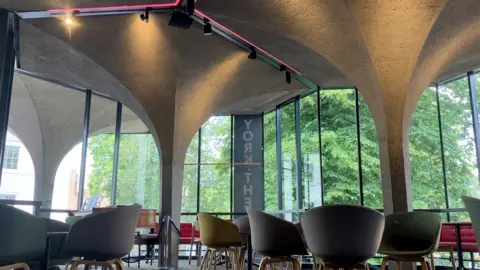 Kit Taylor/BBC The cafe area of York Theatre Royal with concrete pillars replicating the medieval ones, along with chairs.