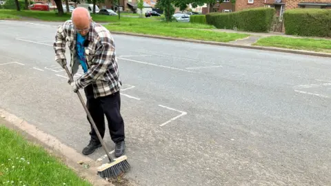 Andy Sherman sweeping the road