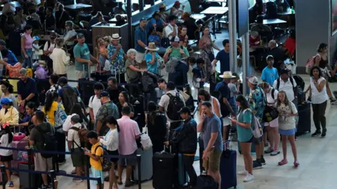 Reuters Dozens of people queue at an airport