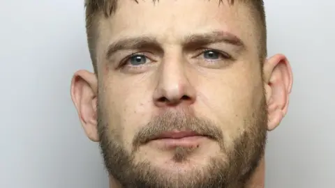 West Yorkshire Police A custody picture of Gareth Brook- a man in his 30s with a short beard.