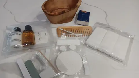 Just.Bathe Contents of a bathing kit including a comb, wooden bowl, and soap. 
