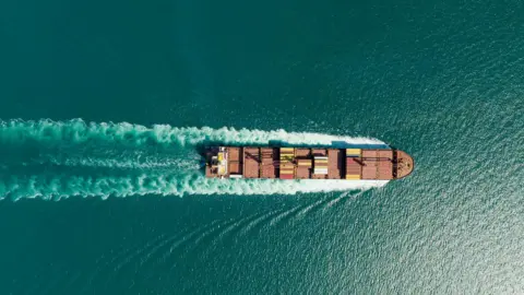 An aerial view of a container ship on a blue-green sea.