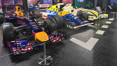 Kate Bradbrook/BBC Nigel Mansell's car in the middle of two other F1 cars. It is blue and yellow and has Canon written across it.