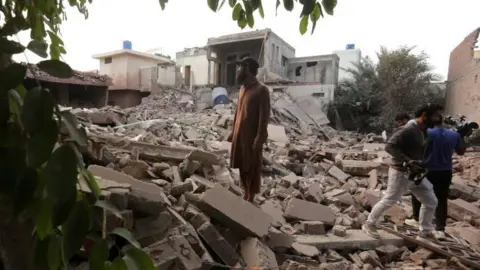 A man standing on the rubble of a building in Muridke 