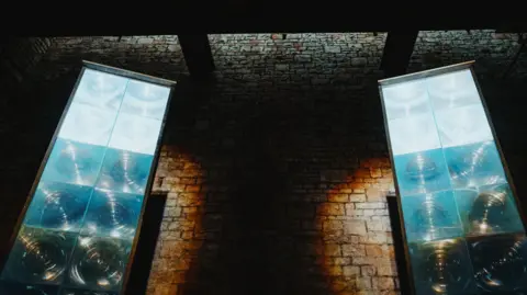 Khali Photography Image taken from a low angle showing two of the panels of light against the brick wall of the bath house.