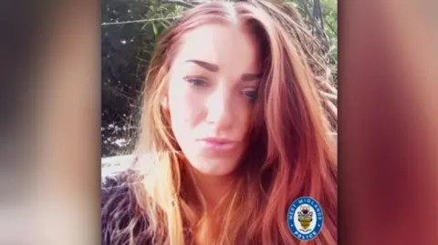 Family handout A woman, Reanne Coulson, has long brown hair and is wearing make up and is smiling at the camera. There is foliage behind her.