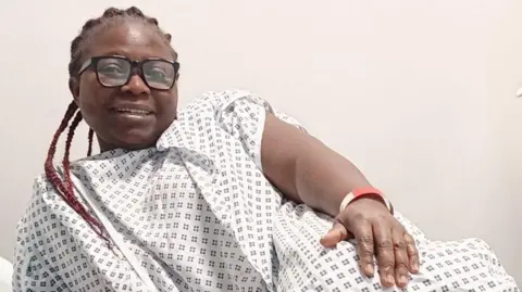 Efetobore Emueje Efetobore Emueje smiling while reclining in a hospital gown